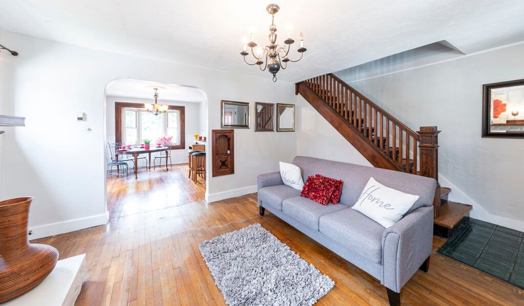freshly painted living room with gray sofa, wooden staircase, and archway leading to dining room in Cranberry Township, PA